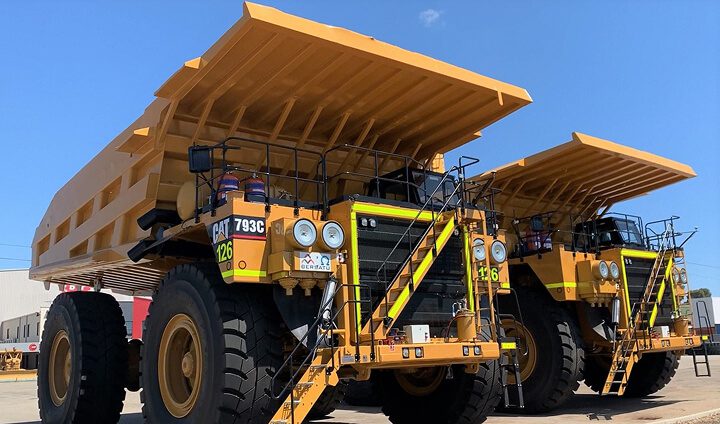 Two CAT 793C off-highway mining trucks parked side by side in a yard.